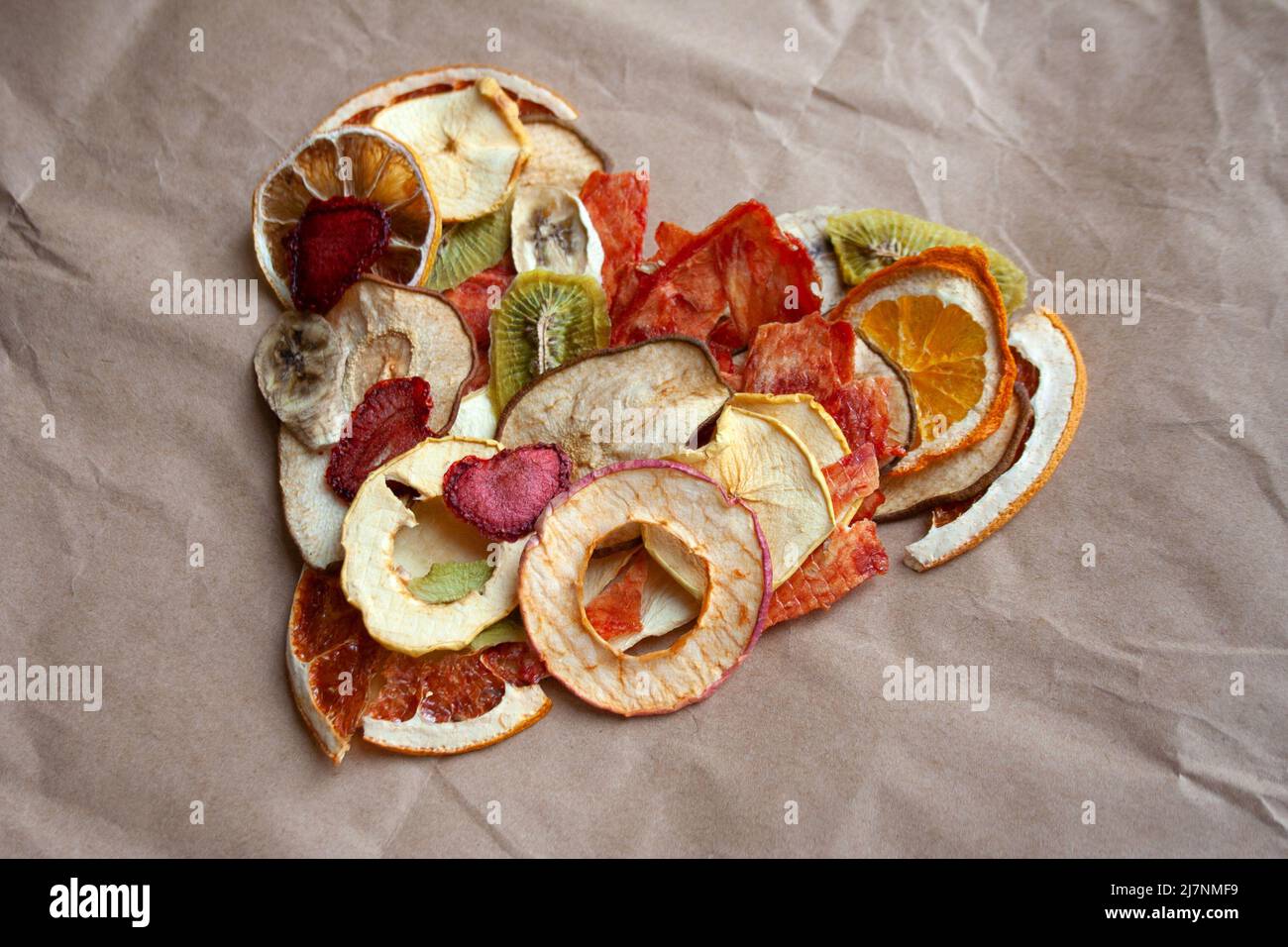 Getrocknete Fruchtchips herzförmige Komposition auf beigefarbenem Papierhintergrund Stockfoto