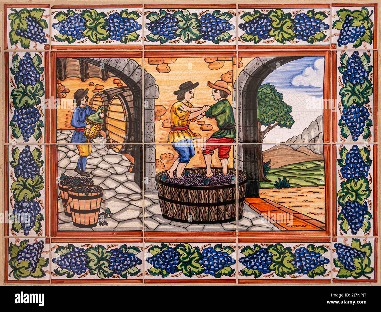 Temecula, CA, USA - 12. April 2022: Europa Village. Wandfliesen Malerei, Phase 4/6 der Weinherstellung. Warme Farben zeigen 3 männliche Figuren, die Trauben pressen Stockfoto