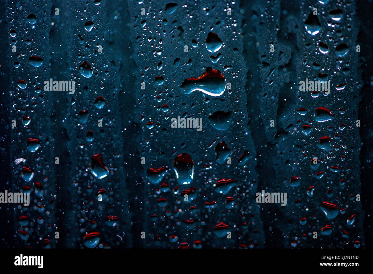 Regentropfen auf einem Fenster mit einem dystopischen / neon futuristischen / dunklen Gefühl Stockfoto