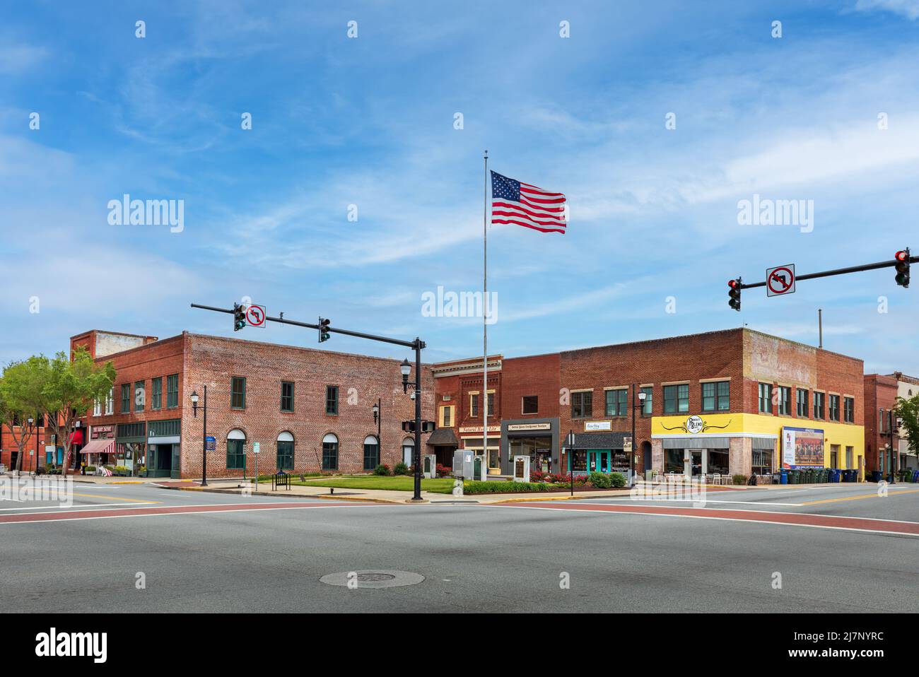 LEXINGTON, NC, USA-8 MAY 2022: Farbenfrohe Weitwinkelansicht der Straßenecke mit einem kleinen Veteranen-Gedenkpark und einer Reihe von Gebäuden auf jeder Seite. Promine Stockfoto