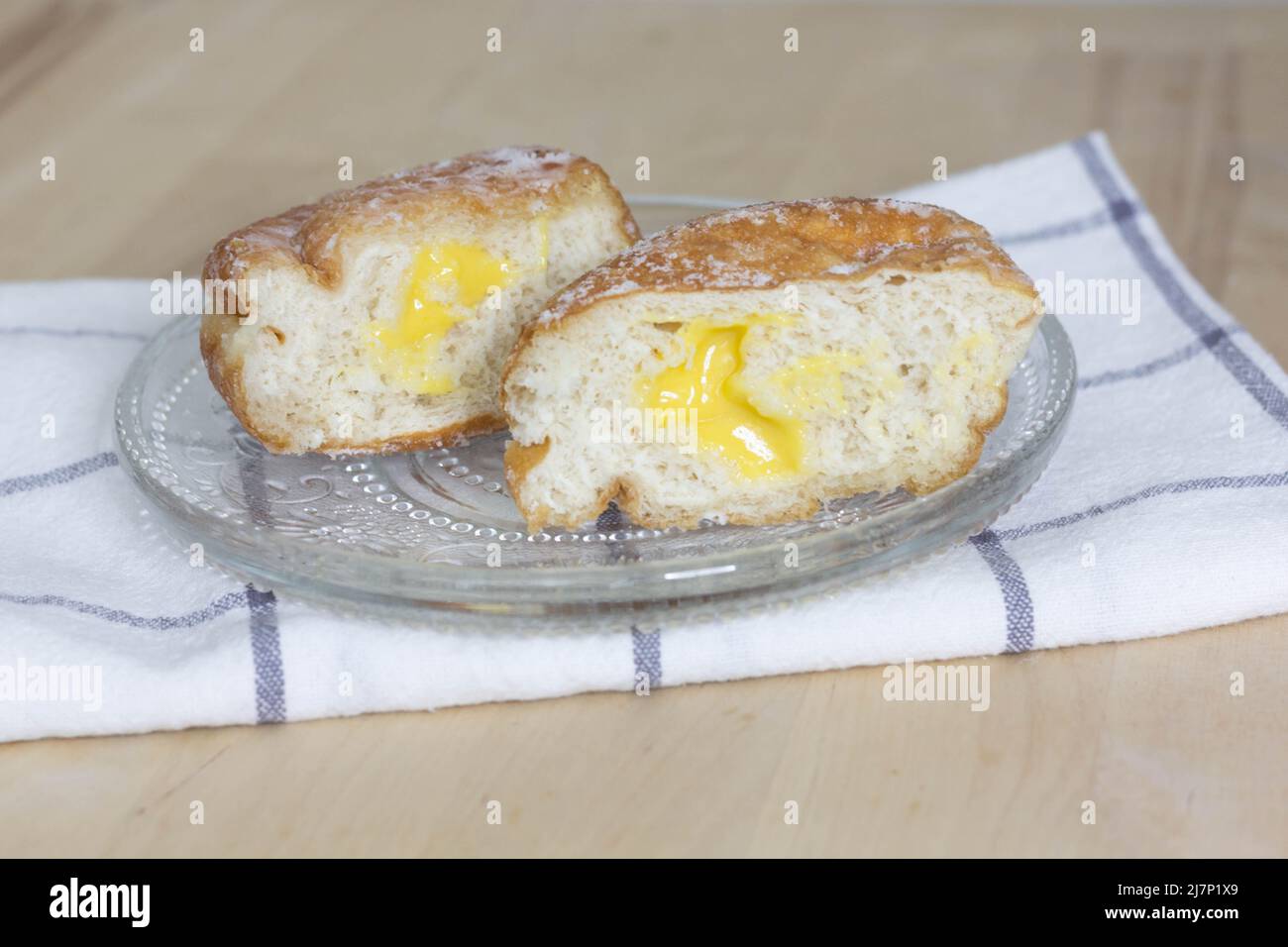 Frittierter Donut (Paczki oder Sisky) mit Zitronenfüllung, Zitronendonut in zwei Hälften geschnitten Stockfoto