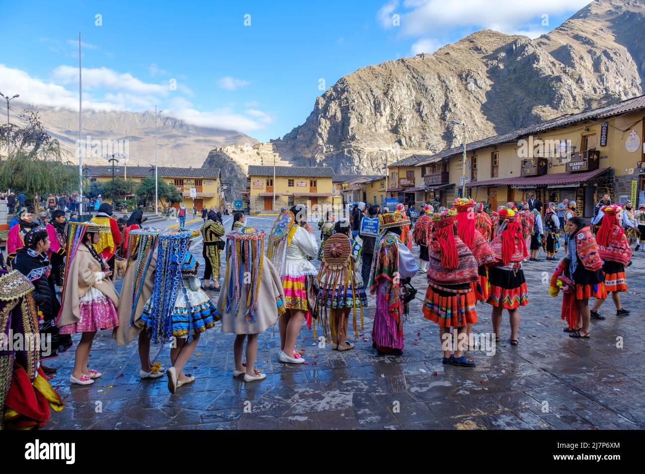 Menschen, die für das Ollantaytambo-Fest, die Plaza de Armas, Berge und Festungsruinen im Hintergrund, das Urubamba-Tal, das Heilige Tal, Peru gekleidet waren Stockfoto
