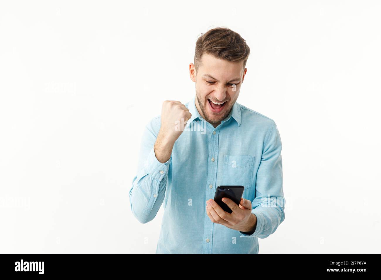 Ein Geschäftsmann hält ein Smartphone und freut sich über eine erfolgreiche Transaktion. Telearbeit, freiberuflich. Stockfoto