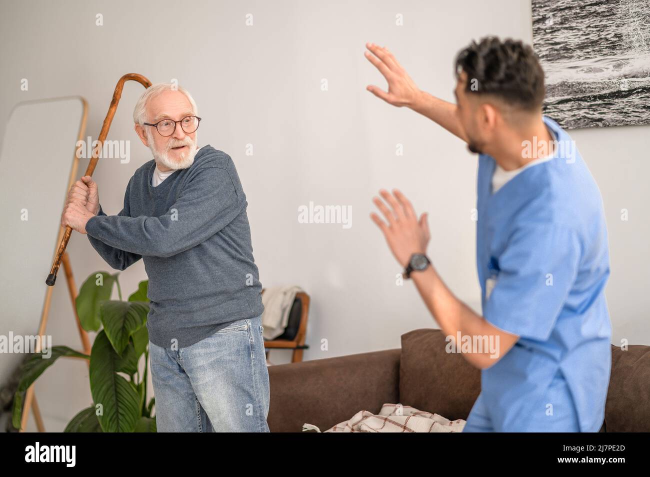 Aggressiver Rentner, der seinen Hausmeister mit dem Gehstock anstreichelte Stockfoto