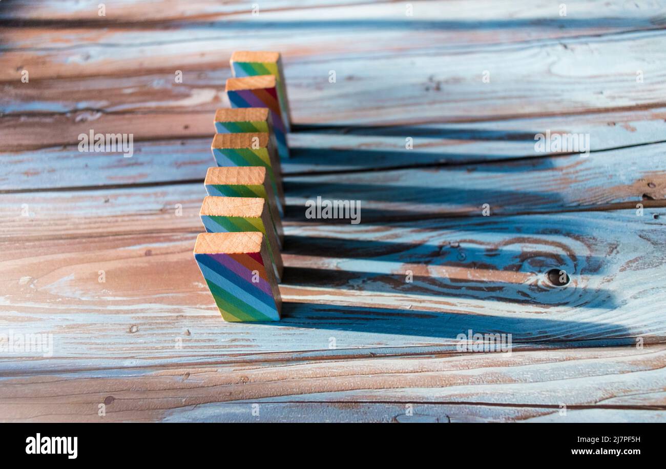 Dominosteine mit farbenfrohem Druck, die auf einen Holztisch gefallen sind Stockfoto