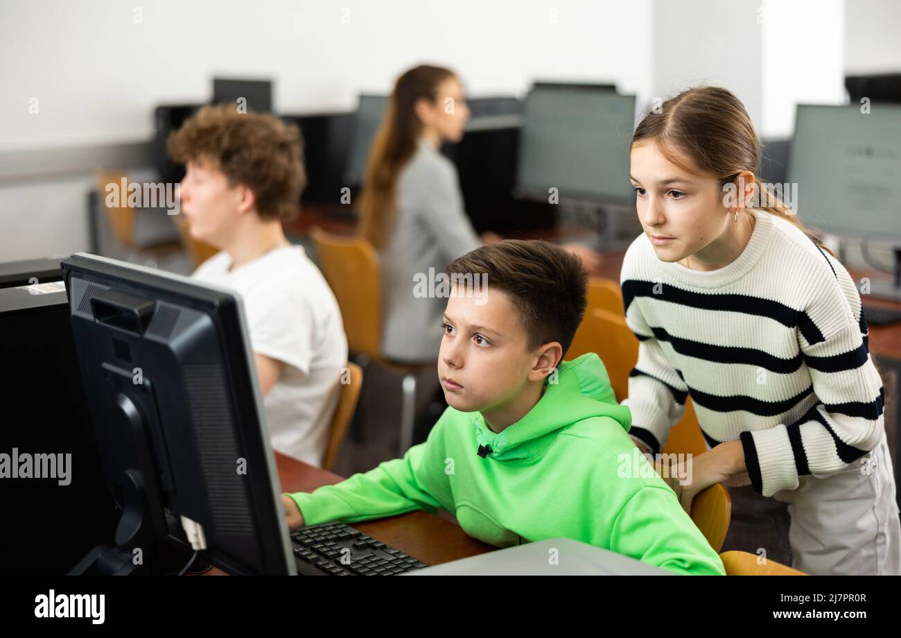 Teenager Junge hilft jungen Mädchen mit PC-Problem in Computer-Klasse Stockfoto