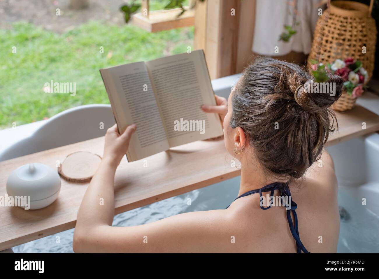 Entspannte Frau, die ein Buch im Whirlpool liest Stockfoto