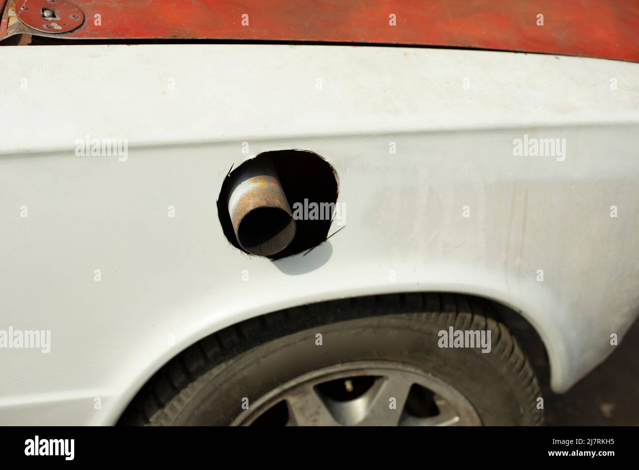 Schalldämpferrohr im Rennwagen. Loch für Auspuffrohr im Auto schneiden. Modernisierter Verkehr. Stockfoto