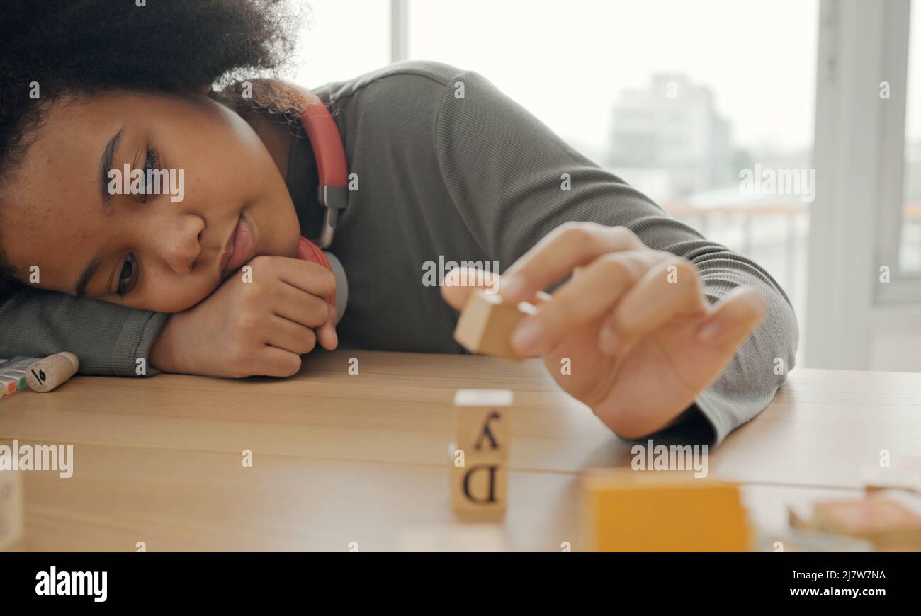 Afroamerikanischer Student, der im Klassenzimmer gemeinsam Holzklotz für die Entwicklung spielt. Stockfoto