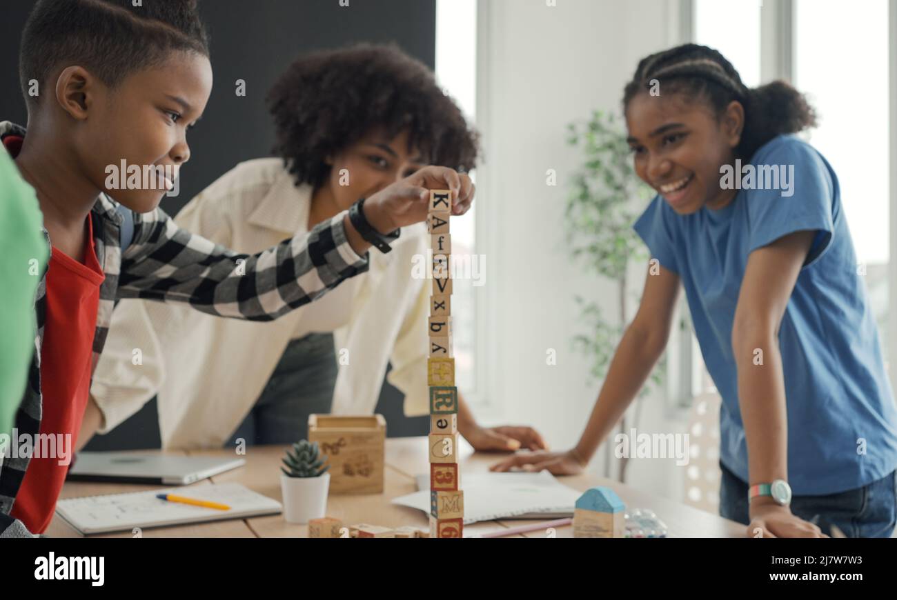 Afroamerikanische Lehrer und Schüler, die Aktivität spielen Block Holz für die Entwicklung zusammen mit genießen und Spaß im Klassenzimmer. Stockfoto