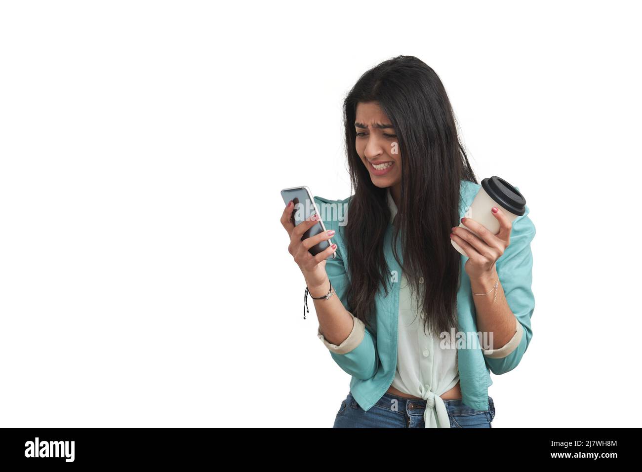 Junge venezolanische Frau, die wütend auf das Telefon schaute, isoliert. Stockfoto