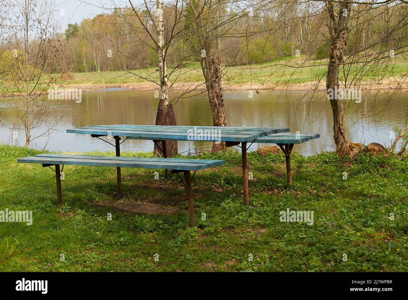 Ein Tisch und zwei Bänke aus Holz am Flussufer Stockfoto