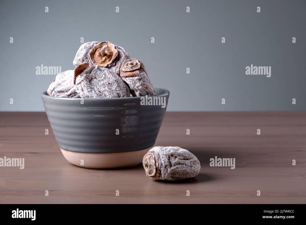 Mehrere getrocknete Kaki in einer Keramikschale. Dies ist ein nützliches Produkt für Erkrankungen des endokrinen und des Verdauungssystems, der Blutgefäße, Beriberi und Anämie. Stockfoto