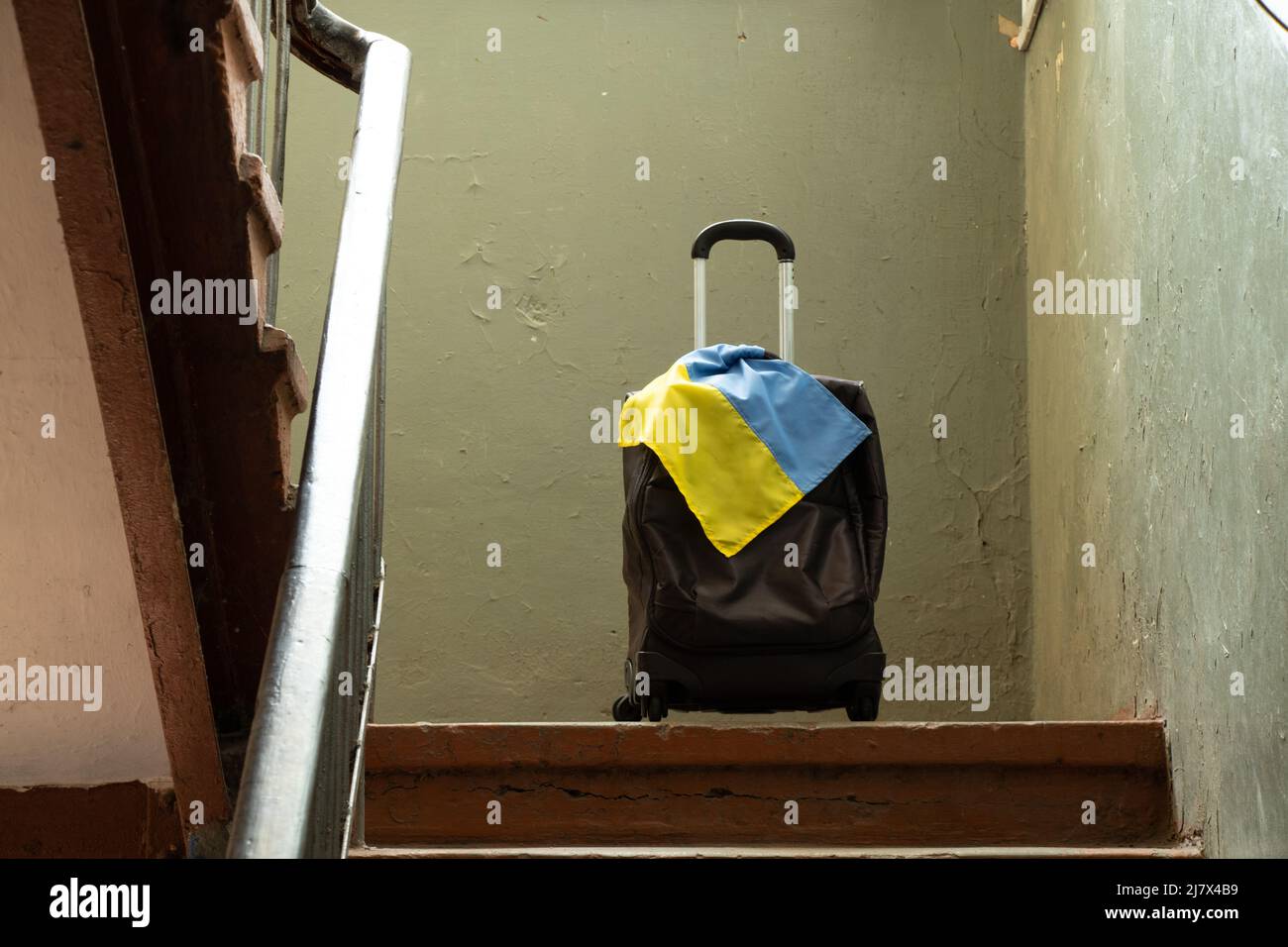 Am Eingang des Hauses steht ein Koffer mit der Flagge der Ukraine, Menschen verlassen wegen des Krieges ihre Heimat, ukrainische Flüchtlinge, der Krieg in U Stockfoto