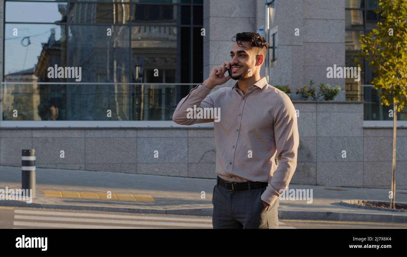 Junger glücklich lächelnder erfolgreicher Geschäftsmann bärtiger Kerl Chef-Chef-Manager steht in der Stadt auf der Straße und spricht auf dem Mobiltelefon und nimmt Anruf Remote an Stockfoto