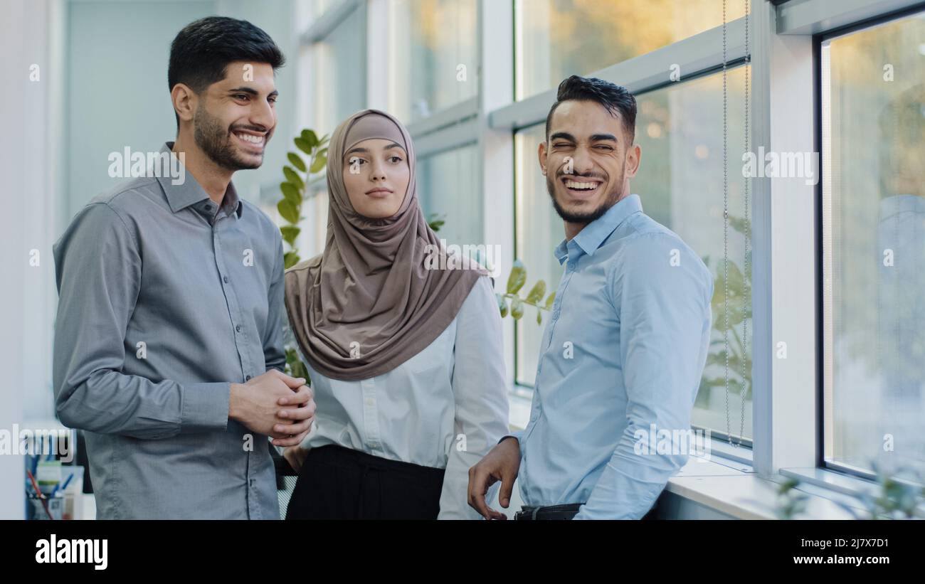 Lächelnde, tausendjährige, multiethnische Mitarbeiter, die während der Büropause Klatsch reden, junge, vielfältige, professionelle Kollegen, die lachen Stockfoto