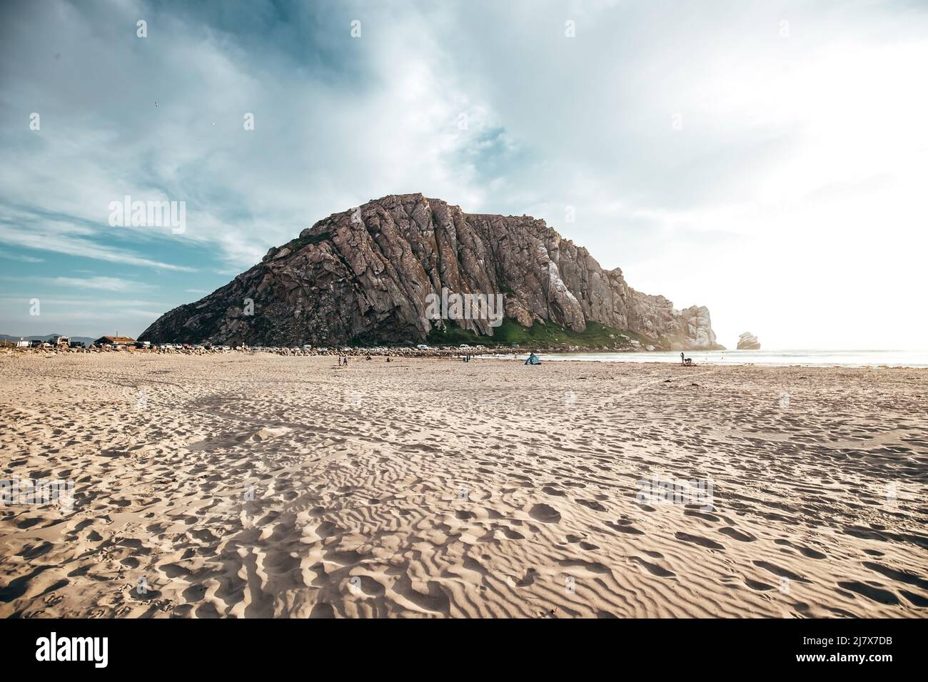 Morro Rock Beach bei Sonnenuntergang in Kalifornien mit einem großen Felsen in der Ferne Stockfoto