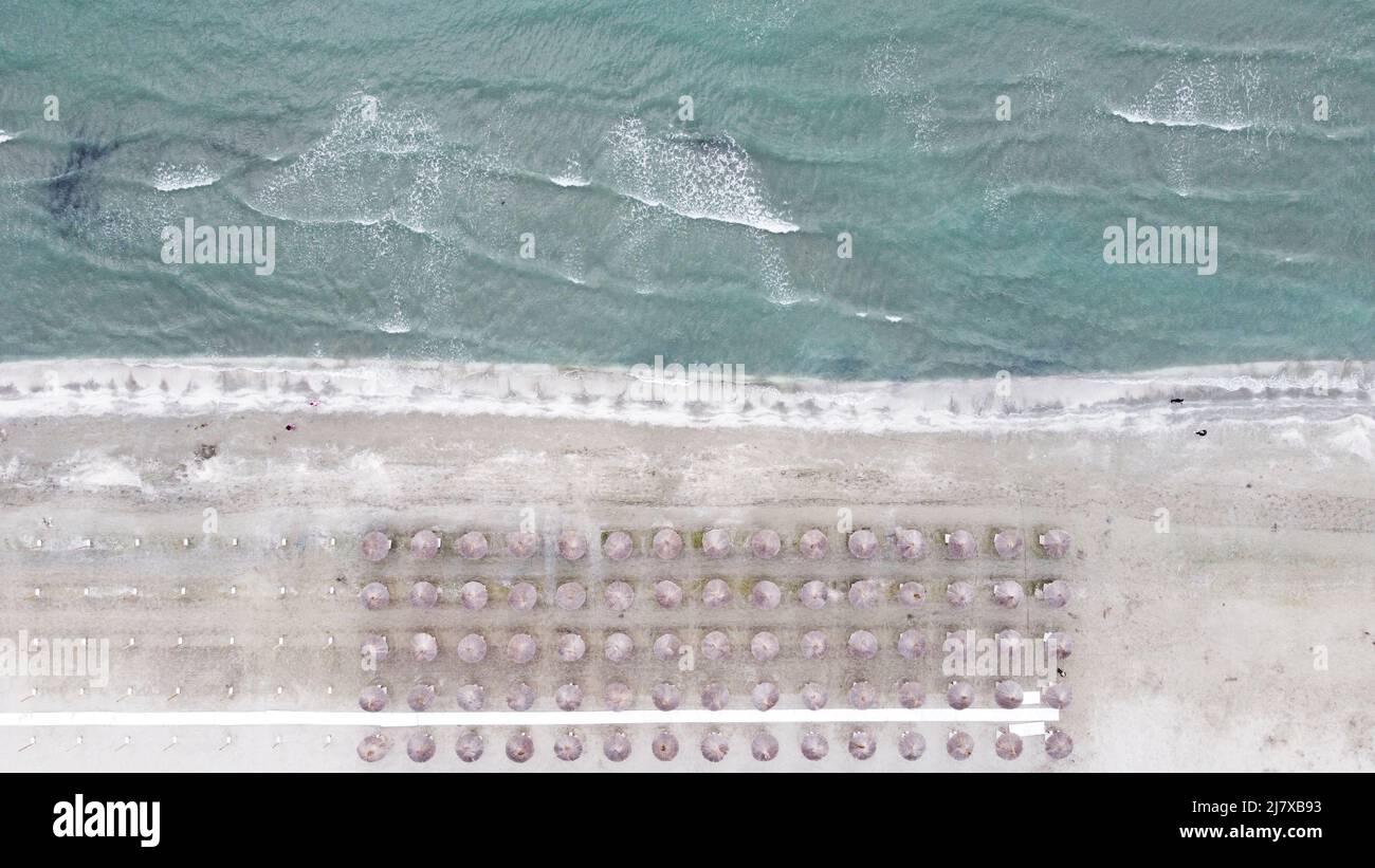 Schöne Luftaufnahme des beliebten rumänischen Strandes mit Sonnenschirmen und dem aufgewühlten Schwarzen Meer im Frühjahr, Mamaia Stockfoto
