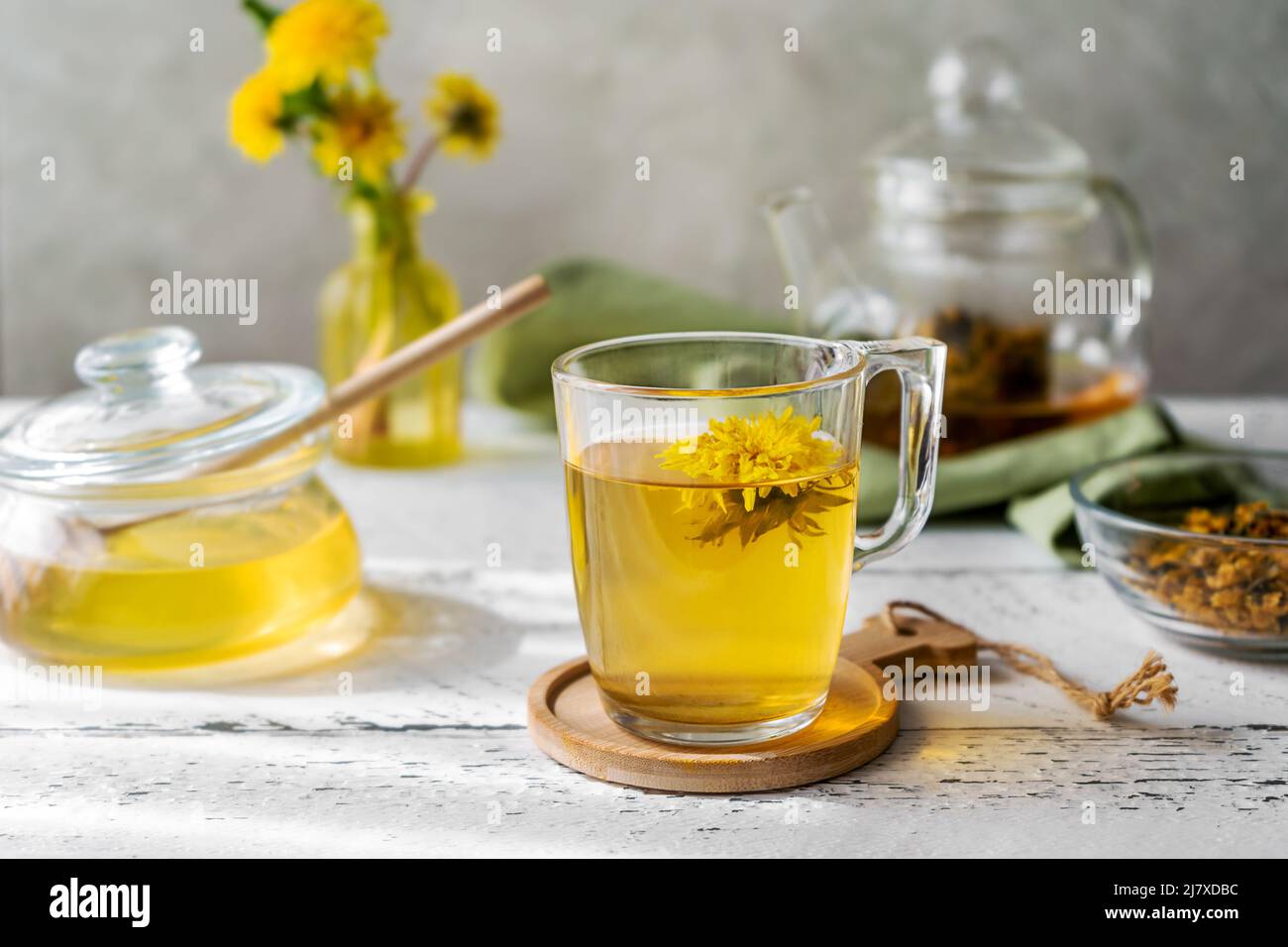 Dandeliontee und Honig auf dem weißen Holztisch mit Teekocher, Dandelionblüten, Trockenmischung für Tee Stockfoto