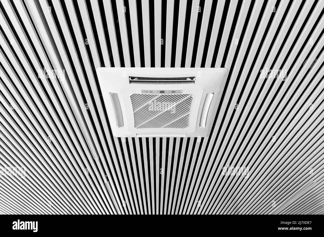 Klimaanlage, die in den Decken im Bürobereich montiert ist. Moderne Decken sind aus weißen und schwarzen Streifen gestaltet. Stockfoto
