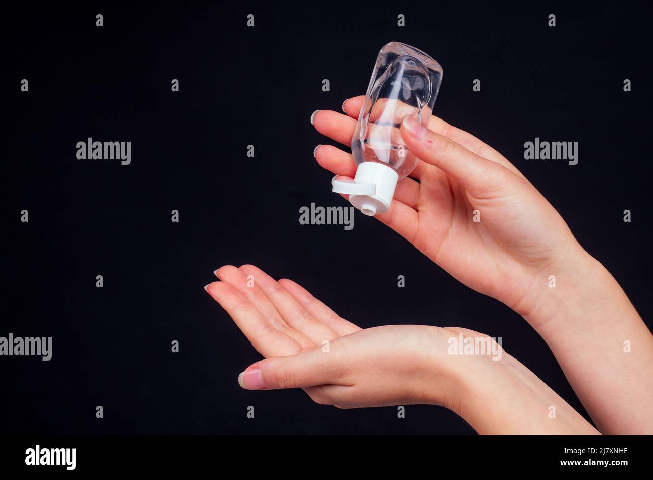 Menschliche Hände verwenden ein Gel, Desinfektionsmittel, antiseptisch in einer Blase, Glas auf schwarzem Hintergrund Stockfoto