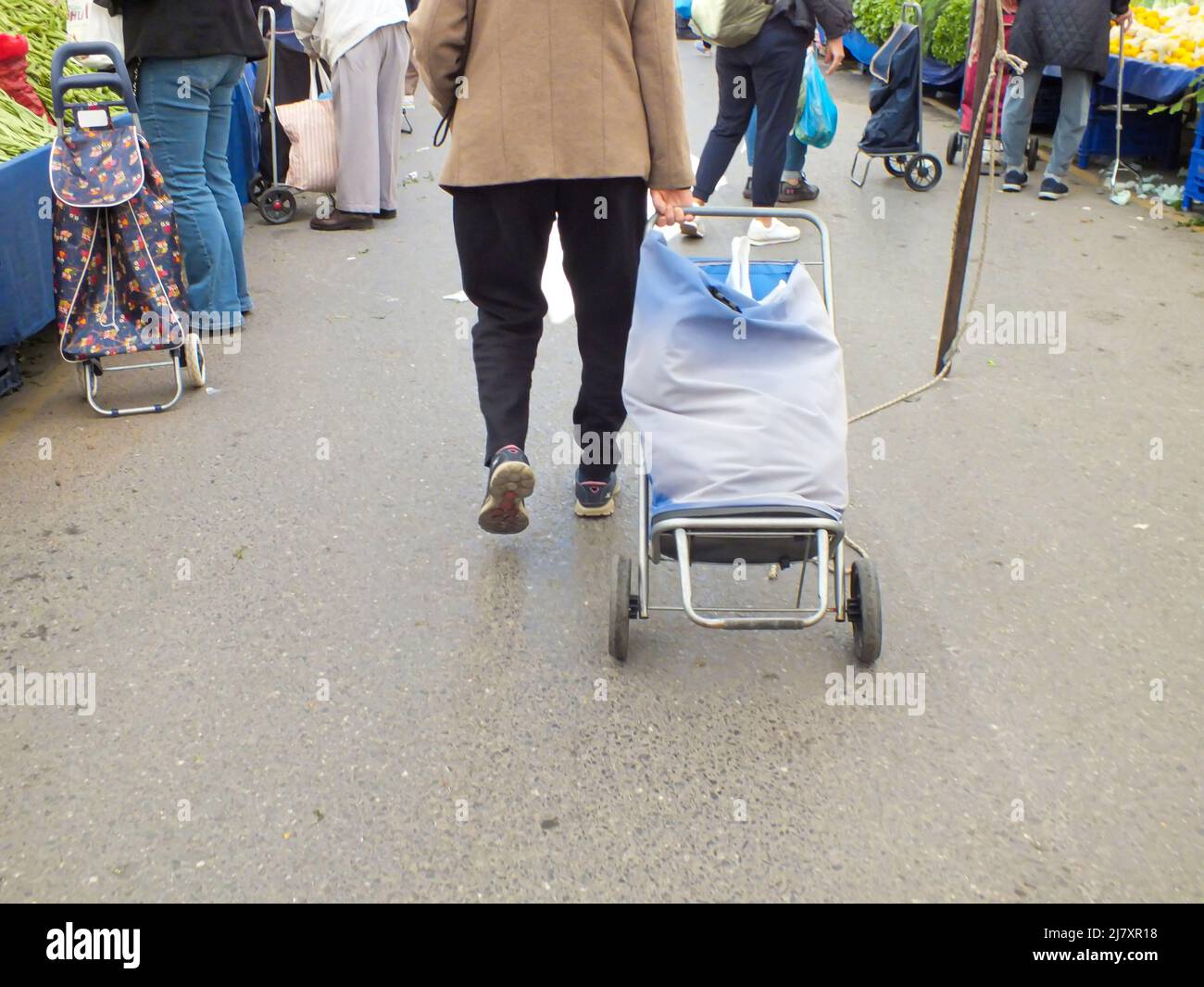 Rückansicht einer älteren Frau, die mit einem Einkaufstasche auf dem lokalen Basar in Istanbul, Türkei, läuft. Leute, die auf dem Bauernmarkt einkaufen Stockfoto