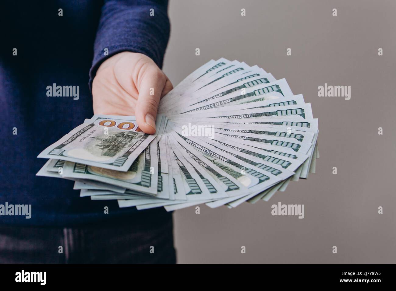 Der Mann hält einen Fan von hundert-Dollar-Scheinen aus. Stockfoto