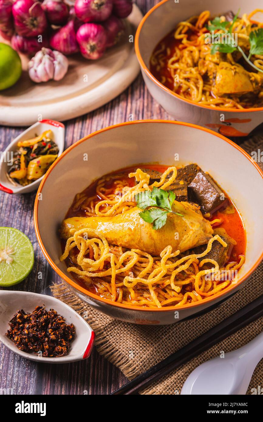 Khao Soi Kai, köstliche Gerichte aus dem Norden Thailands, mit Gewürzen auf dem Tisch arrangiert. Stockfoto