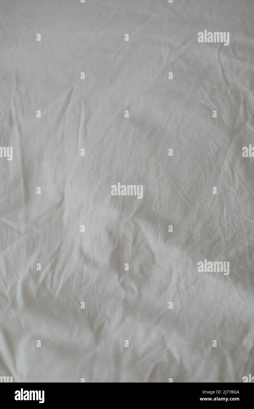 Hintergrund mit Stofftextur. Zerknitterte, zerknitterte Qualität. Blick von oben auf ein unordentliches Bettlaken nach dem Schlafen. Weichfokus Stockfoto