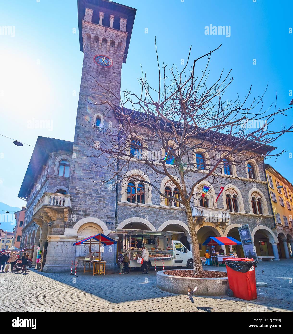 BELLINZONA, SCHWEIZ - 19. MÄRZ 2022: Der herausragende mittelalterliche Palazzo Civico mit hohem Uhrenturm und der Samstagsmarkt auf der Piazza Nosetto, ON Stockfoto