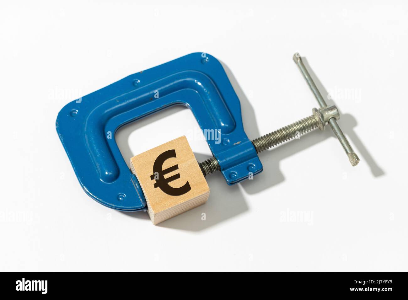 Geldpolitische Straffung. Finanzieller Druck. Klemme komprimiert Euro-Zeichen auf Holzblock Stockfoto