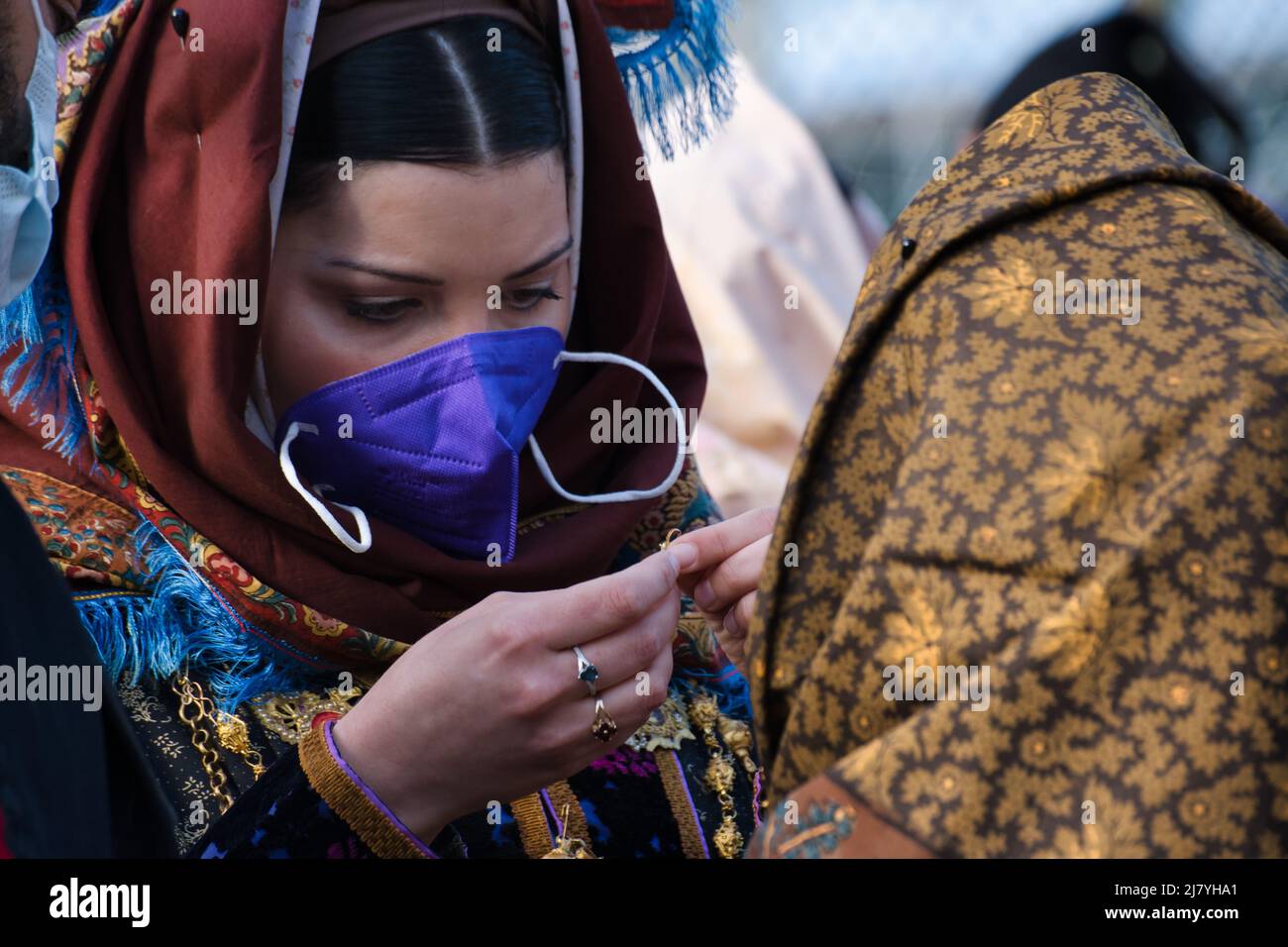 Frau mit Gesichtsmaske macht den letzten Schliff vor der 366-Grad-Religions-/Volksprozession von Sant'Efisio in Cagliari Stockfoto