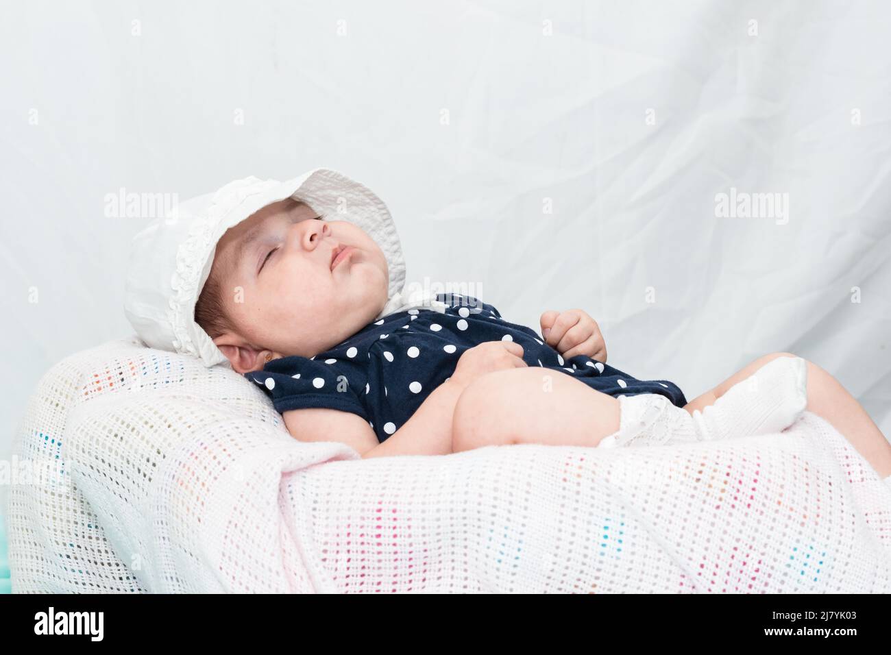 Baby ruht auf einem weißen Kissen, nach einer langen Nacht wach. latina Babe liegt auf einem weißen Kissen auf weißem Hintergrund. Konzept von Gesundheit und Leben. Stockfoto