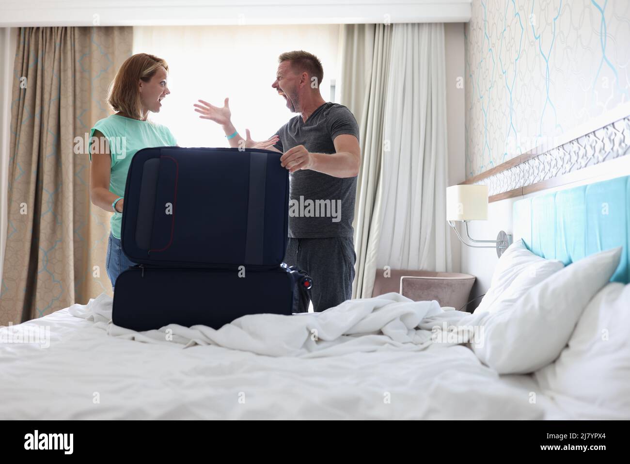 Frau und Mann brüllen sich gegenseitig und streiten, packen Sachen in den Koffer, Pärchen kämpfen Stockfoto