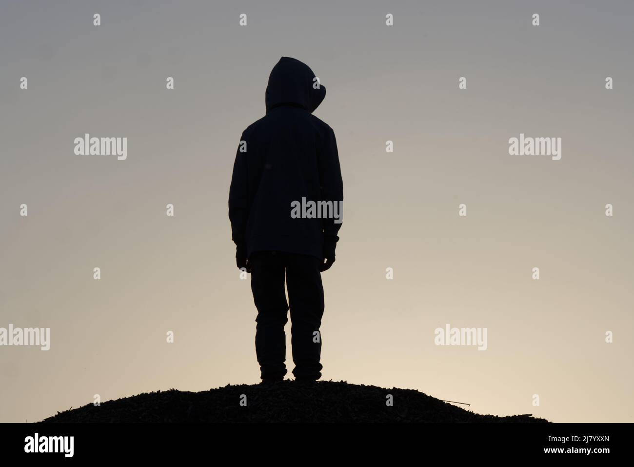 Silhouette eines jungen Teenagers, der auf dem Hügel bleibt. Traurig, Emotion, weinen, Drama, einsam, Depression und unglückliches Konzept Stockfoto
