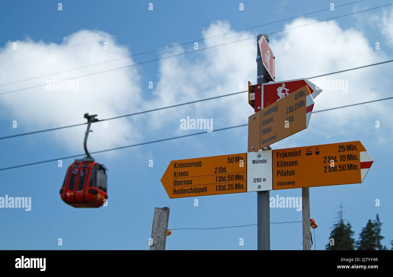 Schilder für verschiedene Bergwanderwege in der Schweiz mit Gondel im Hintergrund Stockfoto