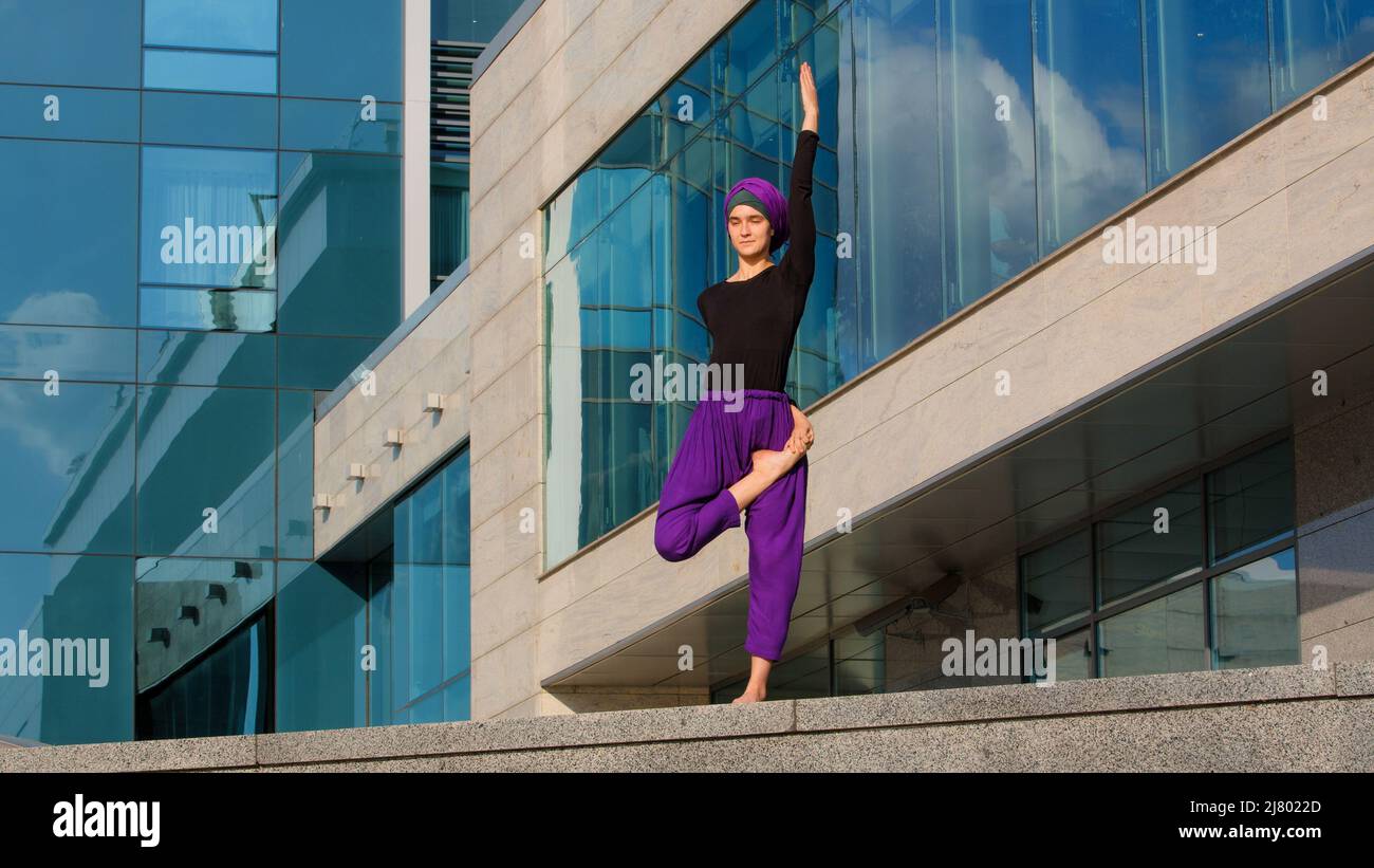 Starke muslimische Frau in Hijab Flexibles junges Mädchen dehnt Yogi Yoga Workout Baum Pose Asana weiblich hebt Bein in der Luft dabei gespaltene Strecke einen Fuß Stockfoto