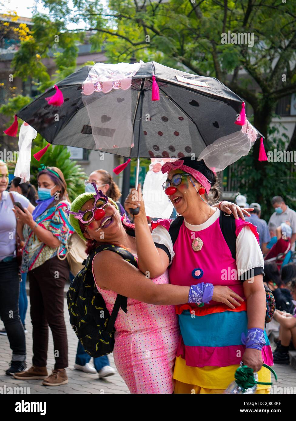 Medellin, Antioquia, Kolumbien - 8 2022. März: Frauen, die als Clowns mit farbenfrohen Regenschirmen in Kleidung gekleidet sind, sind beim Treffen des Marsches für Wome Stockfoto