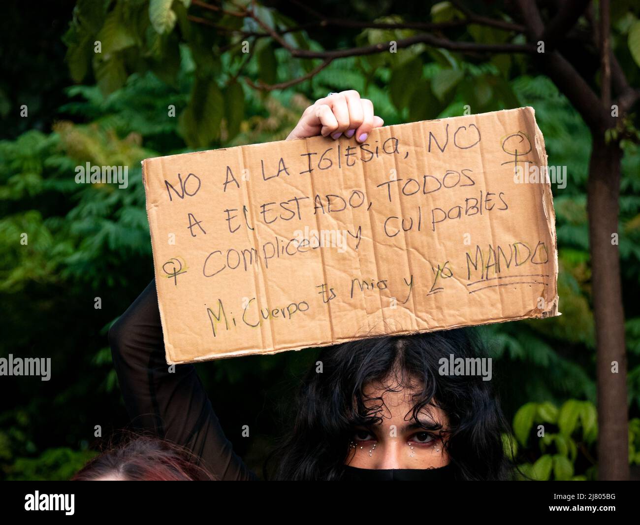 Medellin, Antioquia, Kolumbien - März 8 2022: Frau hält ein Stück Karton, auf dem steht: Nein zur Kirche und Nein zum Staat!, Komplizen und Culpr Stockfoto