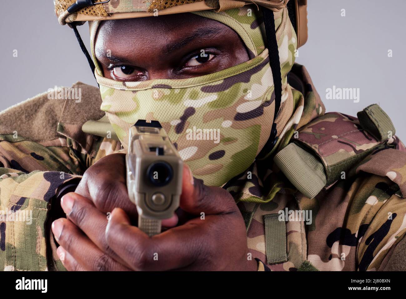 amerikanischer Mann in Tarnanzug mit Pistolenschuss im Studio Stockfoto