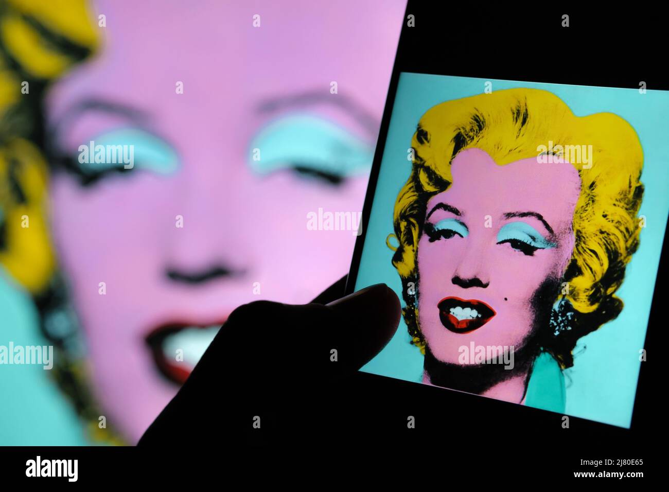 Geschossen Sage Blue Marilyn Kunstwerk auf einem Bildschirm von ipad umgeben von Dollar-Banknoten. Ein Porträt von Marilyn Monroe von Andy Warhol. Stafford, Großbritannien Stockfoto