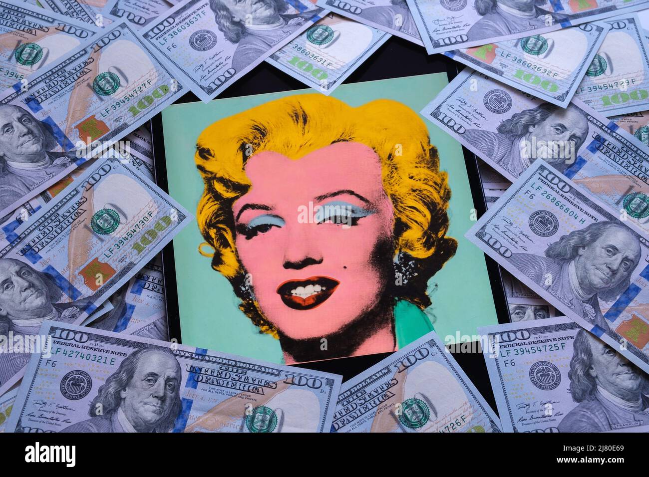 Geschossen Sage Blue Marilyn Kunstwerk auf einem Bildschirm von ipad umgeben von Dollar-Banknoten. Ein Porträt von Marilyn Monroe von Andy Warhol. Stafford, Großbritannien Stockfoto