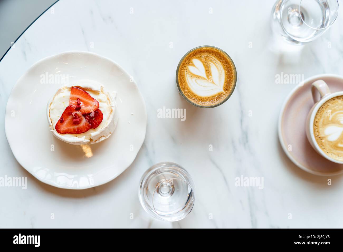 Blick von oben auf Kaffee, Wasser und Baiser-Kuchen mit frischen Erdbeeren Stockfoto