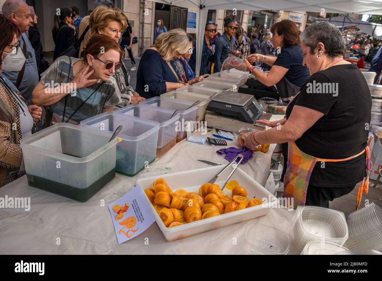 Ein Kunde wird dabei beobachtet, wie er die Qualität der kandierten Früchte, die auf der Messe Sant Ponç zum Verkauf angeboten werden, genau untersucht. Nach zwei Jahren der Unterbrechung im Jahr Covid19 feiert Barcelona erneut die traditionelle Messe Sant Ponç, die sich den Heilkräutern, Honig und kandierten Früchten widmet und seit dem 16.. Jahrhundert stattfindet. Stockfoto