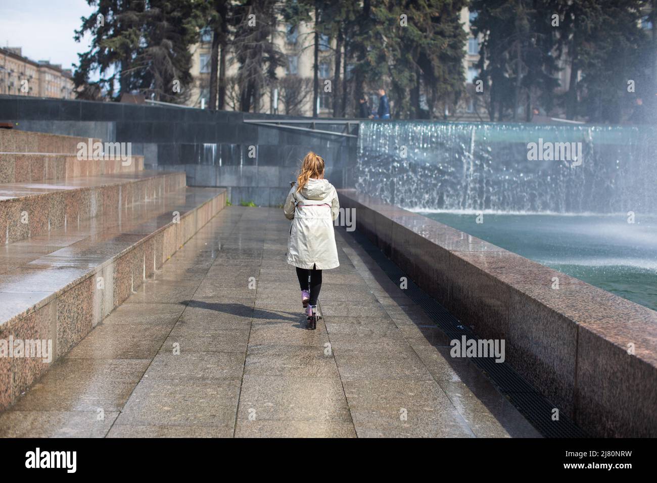 Glücklich kleines nettes Mädchen, das Spaß in spritzt einen Brunnen Stockfoto