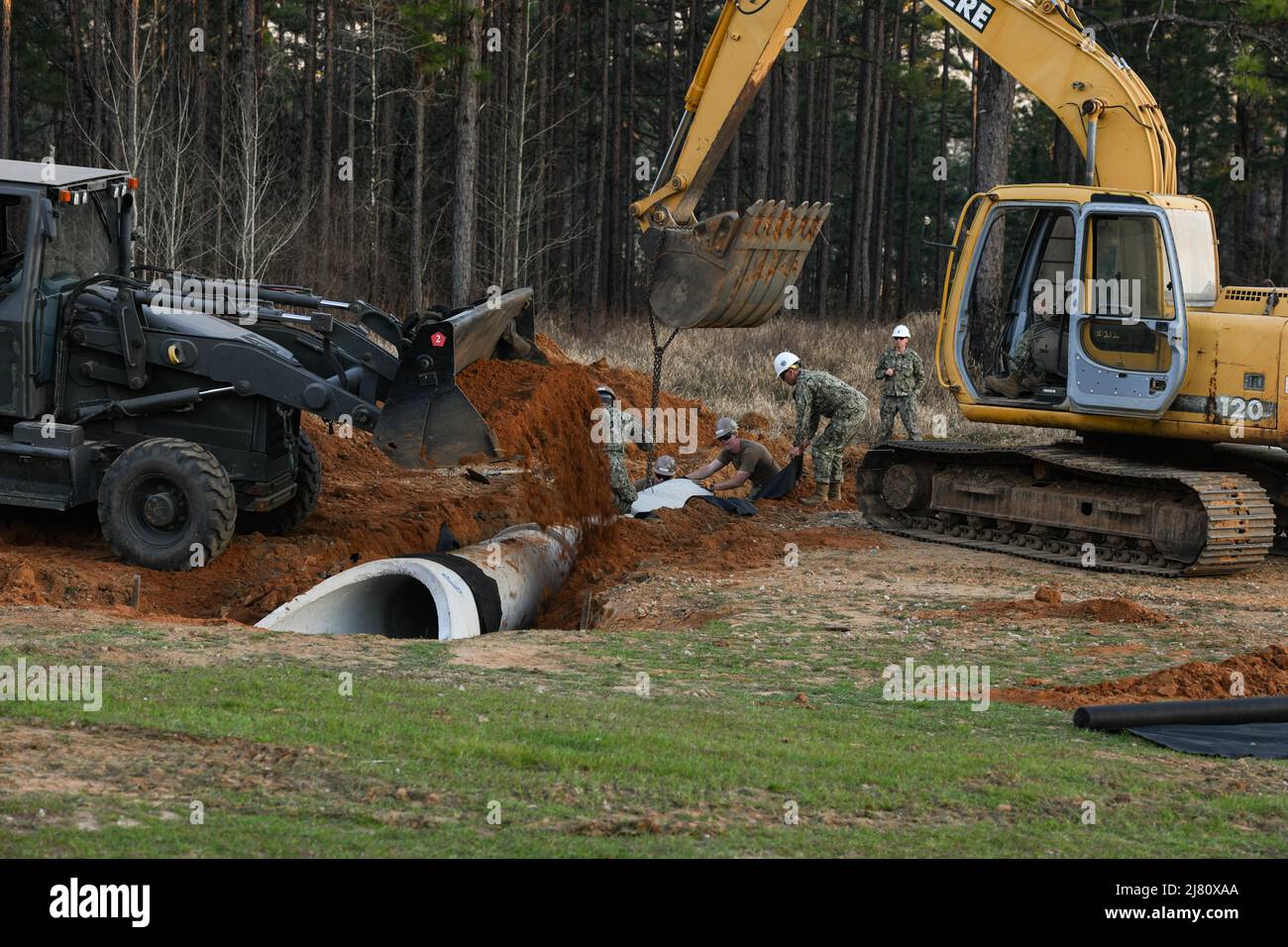 (220304-N-OI810-1340) LAGER SHELBY, Mississippi (4. März 2022) Seebeere, die dem Marineeinsatzbataillon für mobilen Bau (NMCB) 14 zugewiesen sind, richten Stahlbetonrohre während einer Verwerfungsinstallation im zweiten Quartal des Geschäftsjahres 2022 aus und decken sie ab, Regional Training Platform (RTP-2) im Camp Shelby Joint Forces Training Center, 4. März 2022. RTP-2 bot NMCB-14 Seabees praktische Schulungsmöglichkeiten in TCCC, Wartung und Materialmanagement, Hilfsausrüstungen für den Tiefbau, Konvoi-Operationen, Baumaßnahmen, Kampfeinsatz-Center-Operationen und Seeabee-Kampfkrieg A Stockfoto