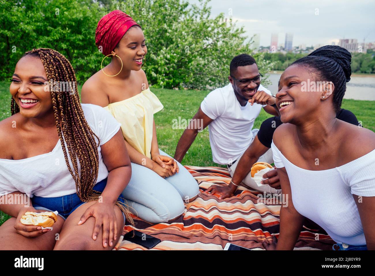 Happy Casual america african people having fun and eating Burger Outdoor Lifestyle, Studenten für eine Pause Sommerabend bewölktes Wetter im Park Stockfoto