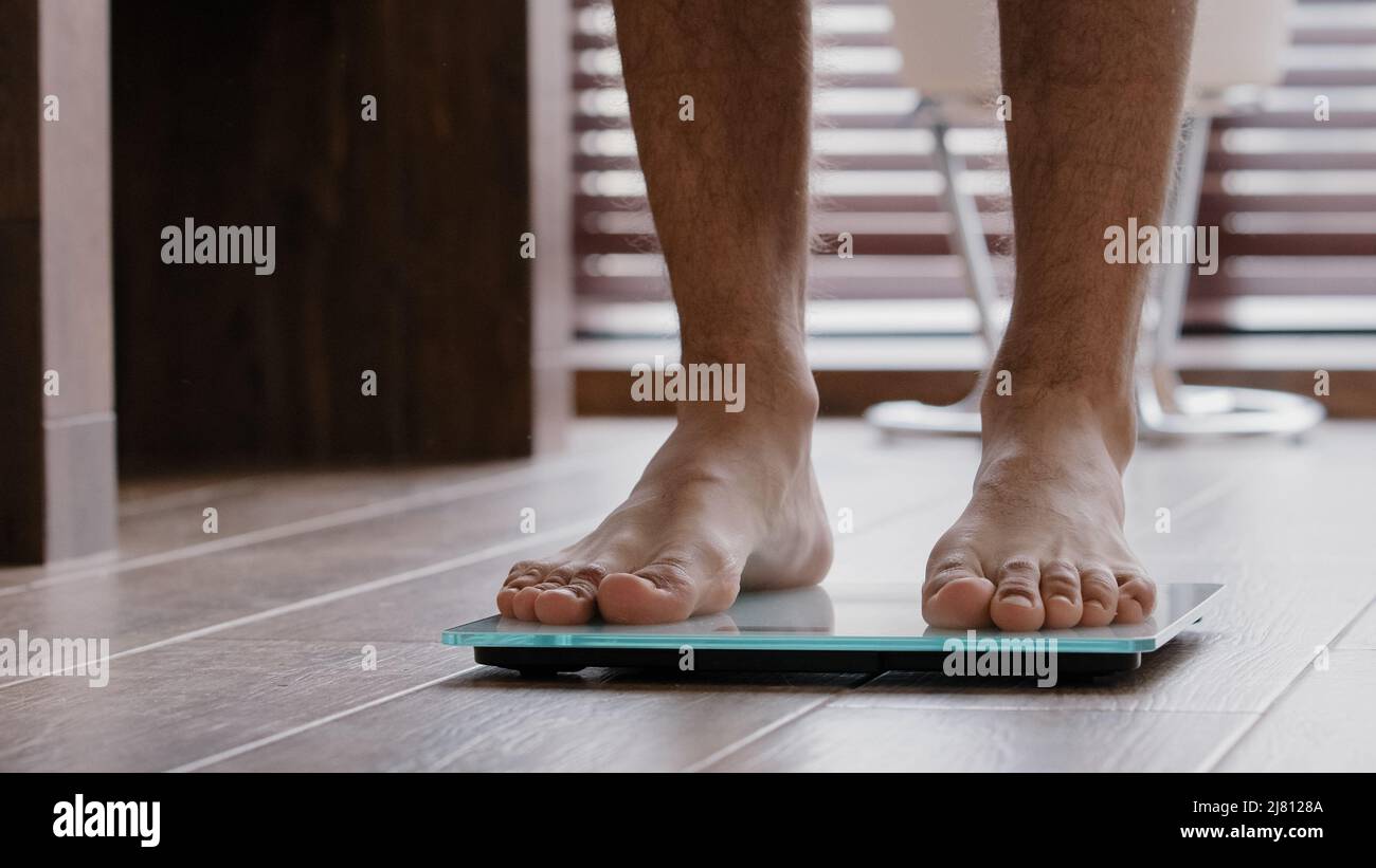 Nahaufnahme männliche Beine schlank dünn sportlich unkenntlich Kerl männlichen Athleten zu Hause im Bad barfuß auf elektronische Waage Kontrolle Gewicht zu gehen Stockfoto