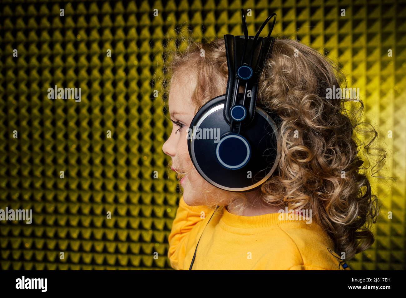 Mädchen blonde lockige Frisur Star-Sängerin Künstler in einer gelben Bluse mit Kopfhörer Aufnahme neuer Song mit Mikrofon. Stockfoto