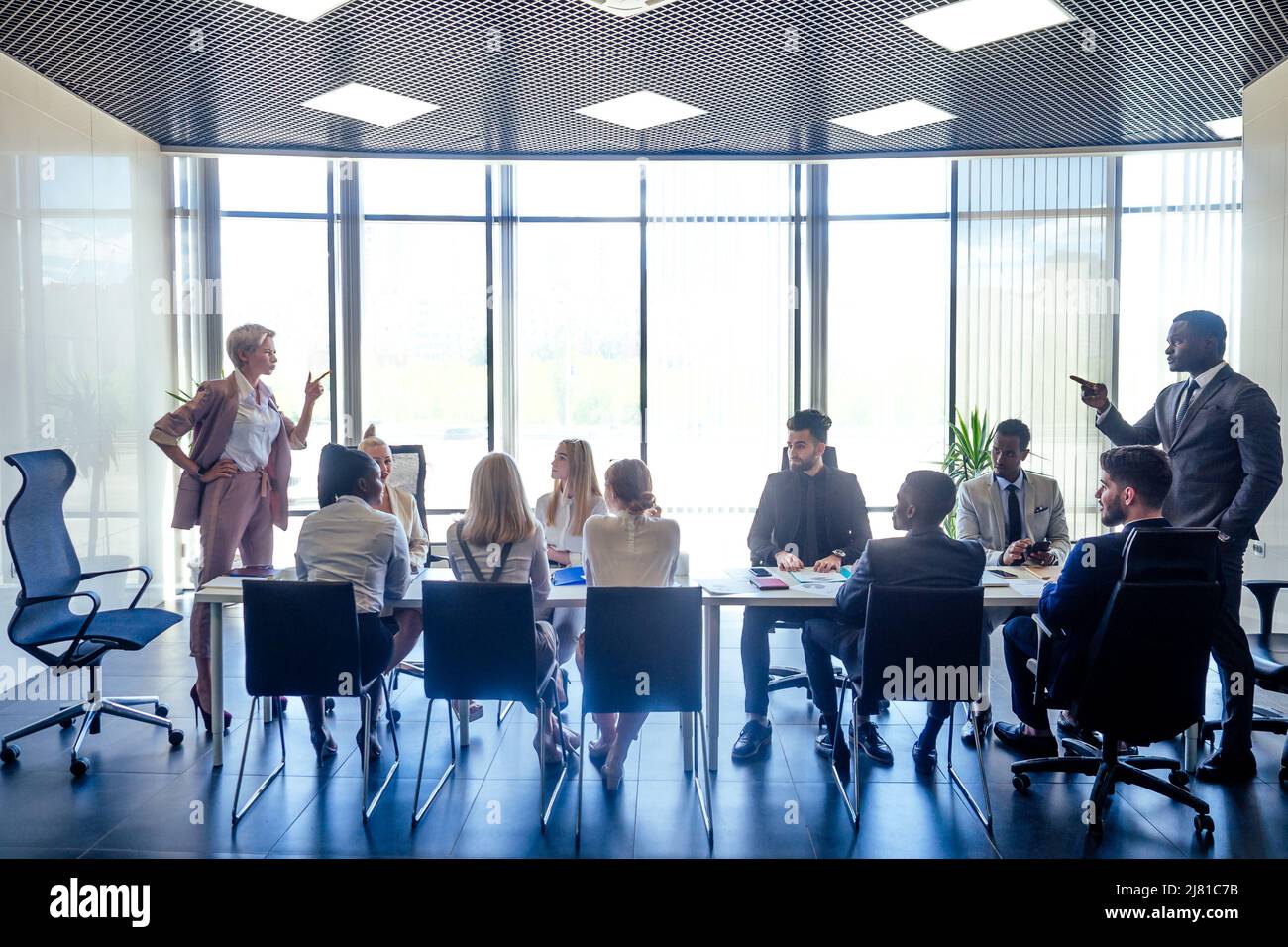 Verärgerte Geschäftsfrau argumentiert Mitarbeiter afroamerikanischer Mann schimpft Mitarbeiter für schlechte Ergebnisse oder diskutiert wichtige Anweisungen bei multirassischen Team Stockfoto
